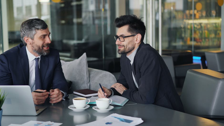 Two businessmen having a discussion over coffee in a modern office setting